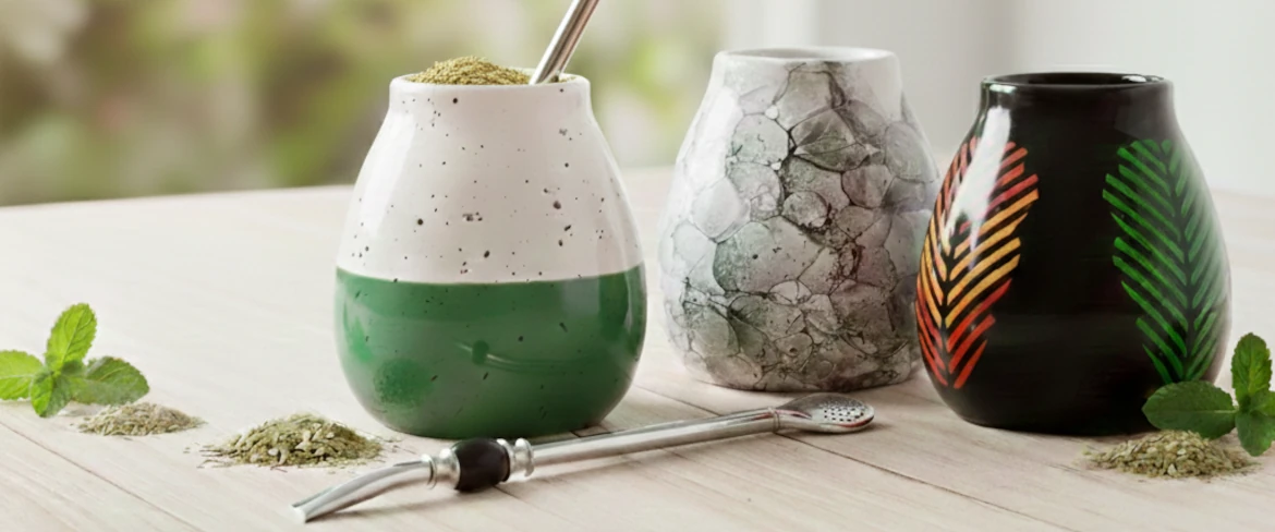 Accessoires pour le maté : différentes tasses à maté et une bombilla sur une table en bois